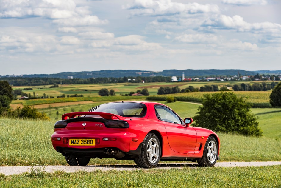 A red Mazda RX-7 that lends its rear reflectors to several Koenigsegg cars